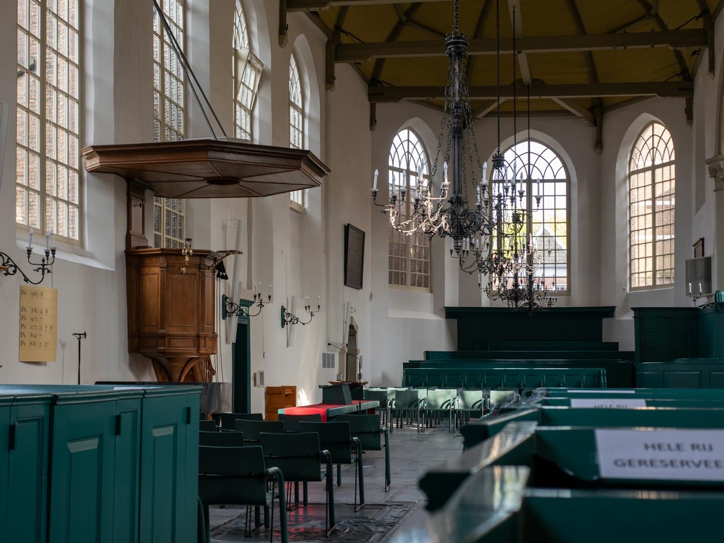 Natuurlijk licht verlicht de houten preekstoel en tealkleurige kerkbanken in een historische kerk.