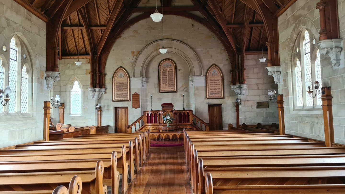 Lege kerkinterieur met houten kerkbanken die naar het altaar leiden.