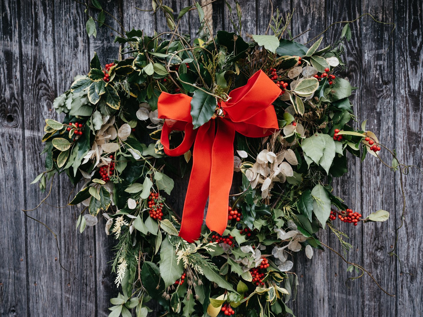 Een kerstkrans hangt aan een rustieke houten muur.