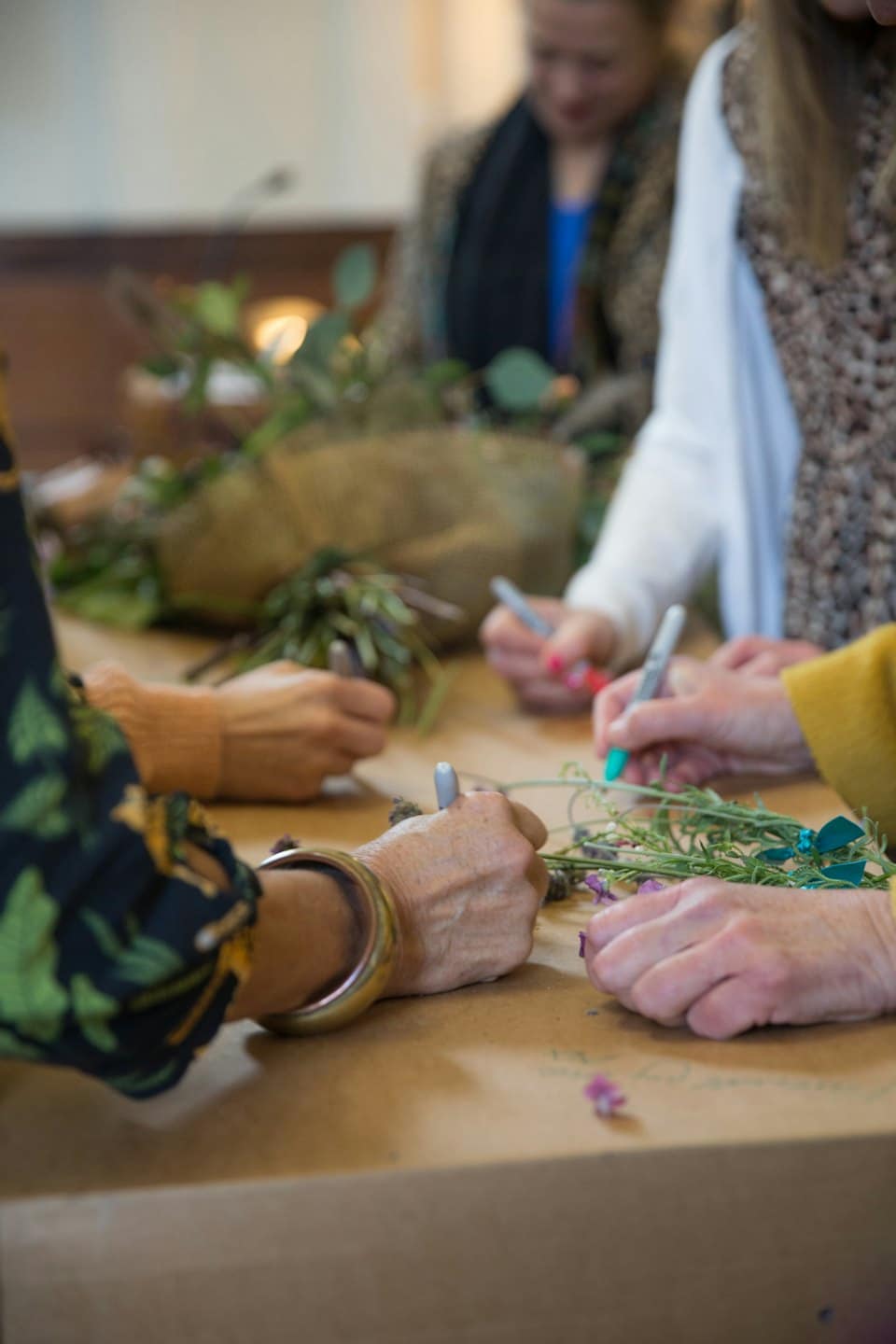 Handen schikken groen en bloemen met kleurrijke stiften.
